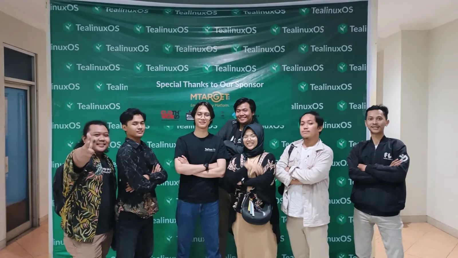 Dinus Open Source Community members in front of a Tealinux OS banner